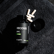 Heroic Muscle Recovix BPC supplement bottle with capsules on a textured black workout towel